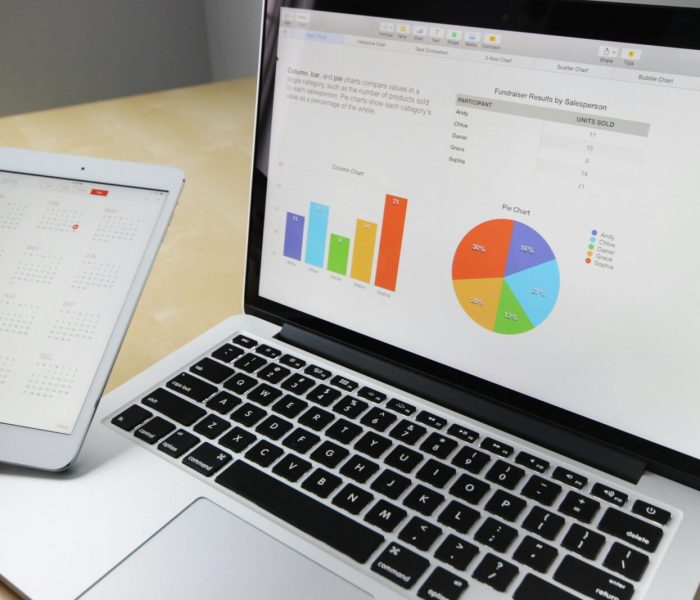 Laptop displaying charts and graphs with tablet calendar for data analysis and planning.