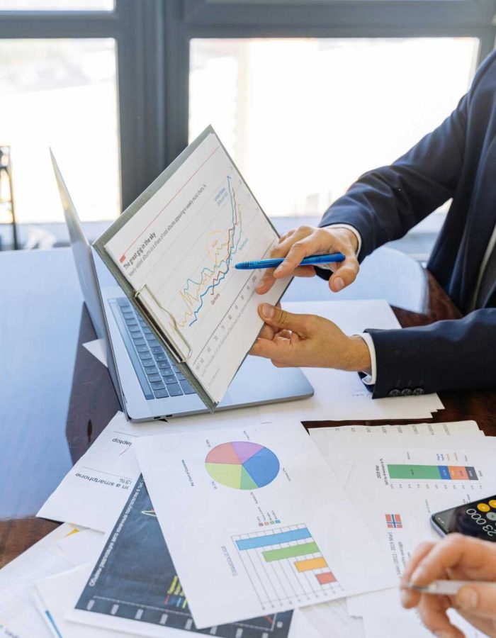 Business professionals discussing financial graphs and charts in an office setting.
